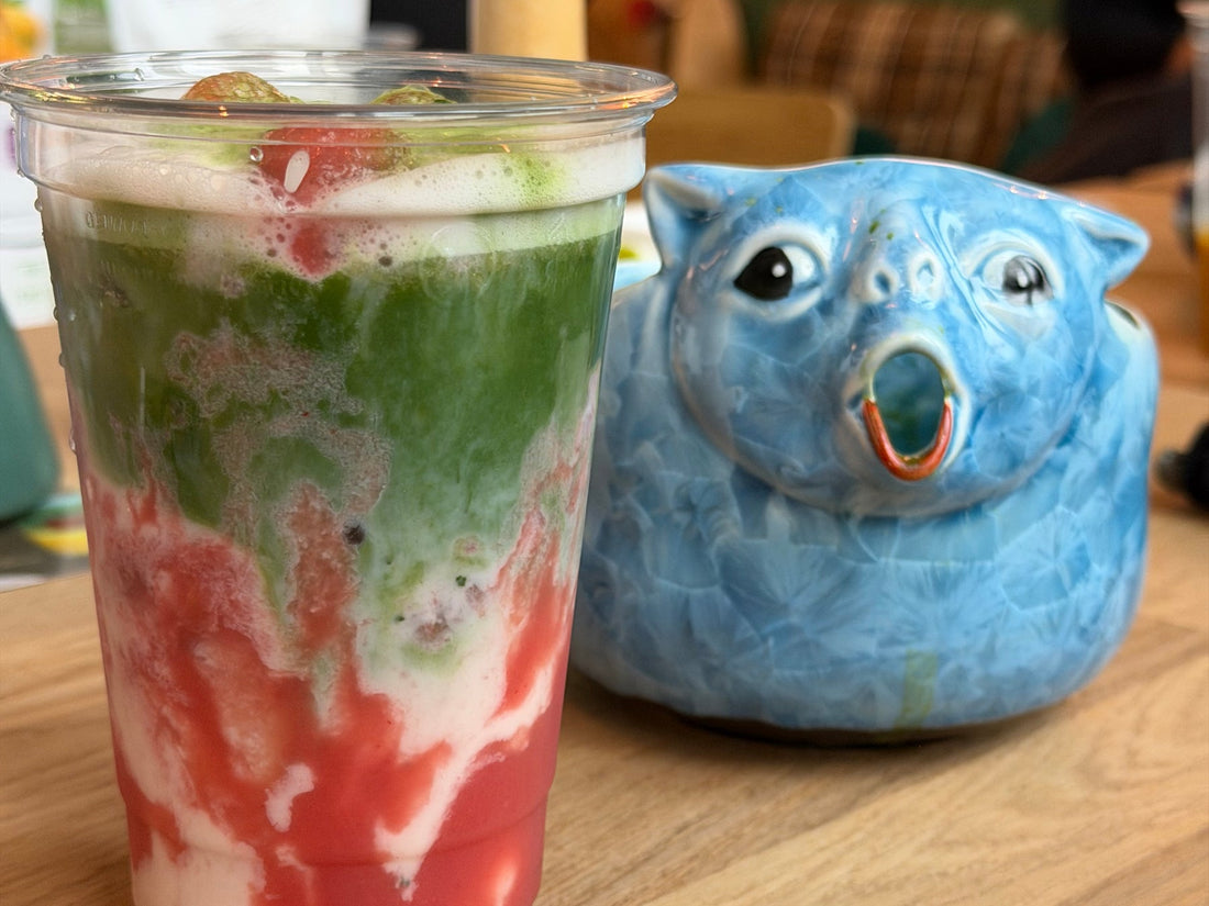Iced strawberry matcha latte next to a blue ceramic cat-shaped bowl at the Morii Teahouse workshop